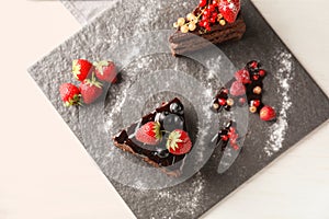 Pieces of delicious chocolate cake with berries on slate plate