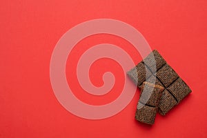 Pieces of delicious hematogen bar on red background, flat lay. Space for text