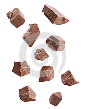 Pieces of delicious milk chocolate falling on background