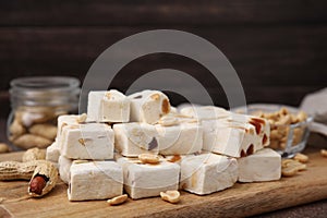 Pieces of delicious nougat and nuts on wooden board, closeup