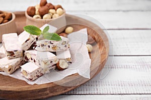 Pieces of delicious nougat and nuts on wooden board, closeup