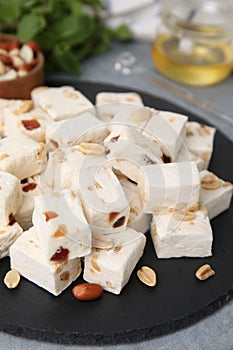 Pieces of delicious nutty nougat on black board, closeup