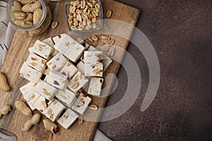 Pieces of delicious nutty nougat on brown table, top view. Space for text