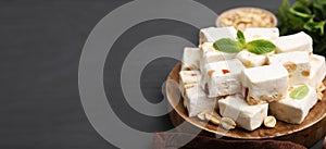 Pieces of delicious nutty nougat on gray wooden table, space for text. Banner design