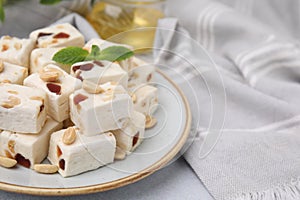 Pieces of delicious nutty nougat on light table, closeup