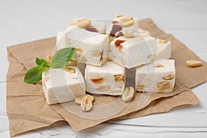 Pieces of delicious nutty nougat on parchment paper, closeup