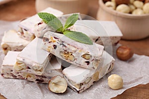 Pieces of delicious nutty nougat on white parchment paper, closeup