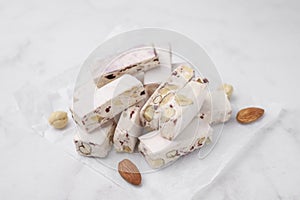 Pieces of delicious nutty nougat on white table