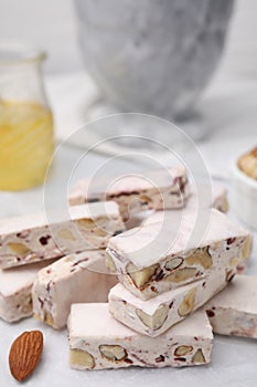 Pieces of delicious nutty nougat on white table, closeup