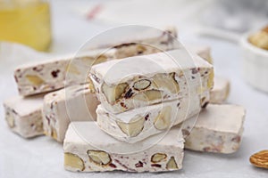 Pieces of delicious nutty nougat on white table, closeup