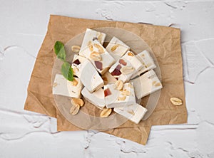 Pieces of delicious nutty nougat on white textured table, top view