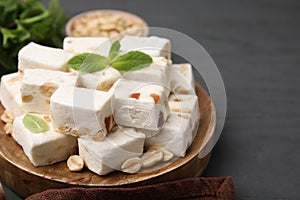 Pieces of delicious nutty nougat on wooden board, closeup