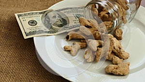 Pieces of dried ginger on a ground and $ 100 usd