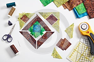 Pieces of fabric laid out in the shape of a patchwork block, sewing and quilting accessories