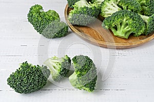 Pieces of fresh green broccoli on white wooden table