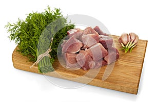 Pieces of fresh pork, bunch of dill and garlic on chopping Board isolated on white
