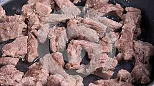 pieces of fried beef in a frying pan are fried in oil close-up. cooking homemade food