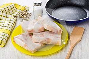 Pieces of frozen pollock, napkin, salt, condiment, spatula, frying pan