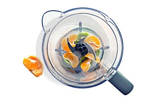 Pieces of fruit in a blender. Juicy tangerines and kiwis.