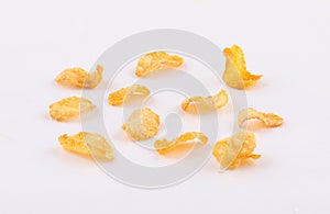Pieces of golden corn flakes on white background
