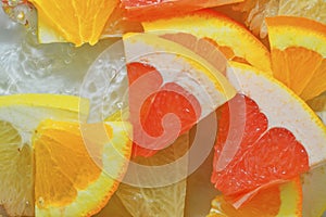 Pieces of grapefruit, orange fruit and honey pomelo in liquid with bubbles. Slices of grapefruit, orange fruit and honey