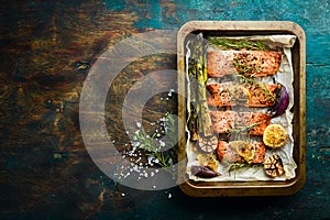 Pieces of grilled salmon in a metal tray with vegetables and rosemary. Recipe. Seafood.