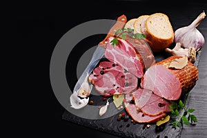 Pieces of homemade smoked pork ham on black background and space