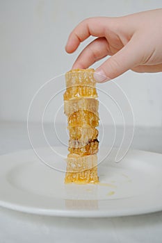 Pieces of honeycomb with honey on the white plate closeup with nand. Vertical photo