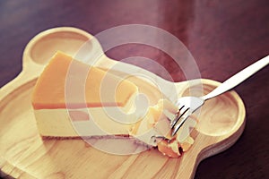 Pieces of Mango cheesecake on wooden plate.