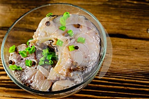 Pieces of the marinated carp in bowl on wooden table