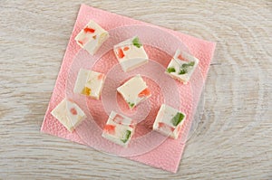 Pieces of marshmallow with marmalade on paper napkin on wooden table. Top view