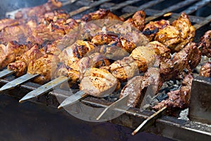 Pieces of meat are friend on fire on skewers on grill. close up