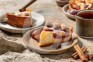 Pieces of The New York Times Famous Plum Torte or pie with spices and tea on textured background rustic style