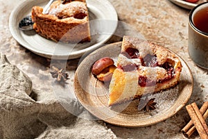 Pieces of The New York Times Famous Plum Torte or pie with spices and tea on textured background rustic style