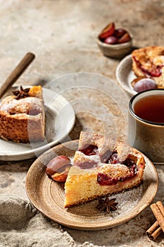 Pieces of The New York Times Famous Plum Torte or pie with spices and tea on textured background rustic style. Space for