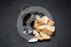 Pieces of parmesan or parmigiano cheese, wine and grapes