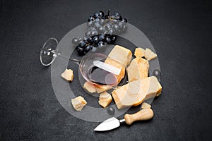 Pieces of parmesan or parmigiano cheese, wine and grapes