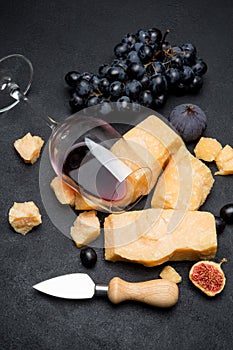 Pieces of parmesan or parmigiano cheese, wine and grapes