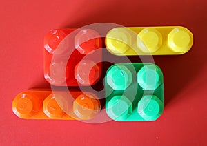 Pieces of plastic rainbow multicolored buildable toy blocks formed and arranged on red background