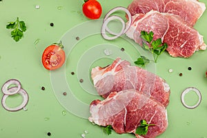 Pieces of pork meat with parsley, purple onion rings and tomato, raw fresh steaks concept
