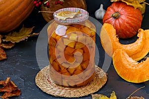 Pieces pumpkin in jar located on a dark background, harvesting vegetables for the winter, horizontal orientation