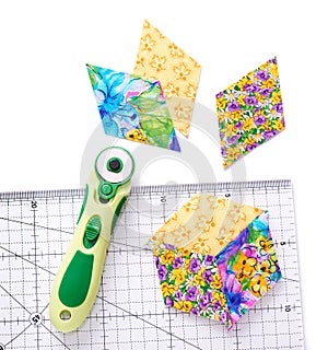 Pieces of quilt with rotary knife and ruler on white surface