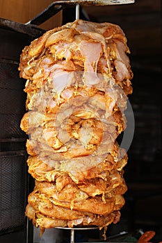 Pieces of raw chicken soaked in seasonings and strung on a spit for shawarma