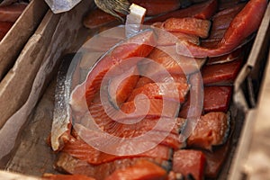 Pieces of red smoked fish in a box at the market. Sea delicious dietary delicacy. Close-up