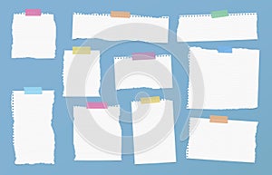 Pieces of ripped white ruled note paper are stuck with colorful sticky tapes on blue background photo