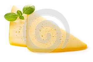 Pieces of semi-hard or hard yellow cheese with holes and basil leaf isolated on a white background