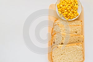 Pieces of sliced fresh corn bread on a wooden Board and a plate of corn grains on the table. White isolated background, top view,