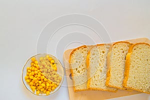 Pieces of sliced fresh corn bread on a wooden Board and a plate of corn grains on the table. White isolated background, top view,