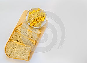 Pieces of sliced fresh corn bread on a wooden Board and a plate of corn grains on the table. White isolated background, top view,