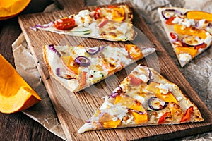 Pieces of tarte flambee with pumpkin, red onions and cheese
